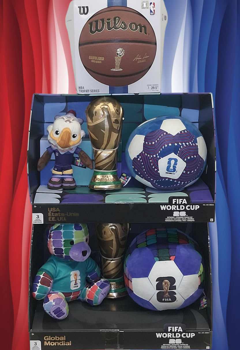 A set of FIFA World Cup merchandise displayed on a white background, including a Wilson basketball, two FIFA World Cup balls, two gold trophies, and two plush mascots in their original packaging.