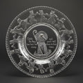 Decorative glass plate with engraved design and text on a black background