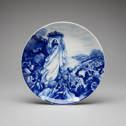 Decorative plate with a blue and white religious scene on a dark background