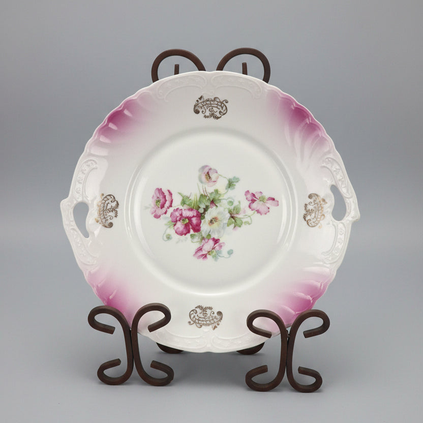Decorative plate with floral design on a stand against a black background