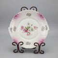 Decorative plate with floral design on a stand against a black background