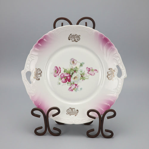 Decorative plate with floral design on a stand against a black background