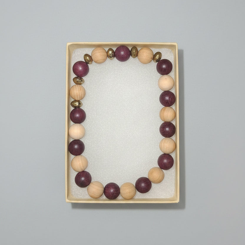 Beaded bracelet in a box with other jewelry items on a dark surface