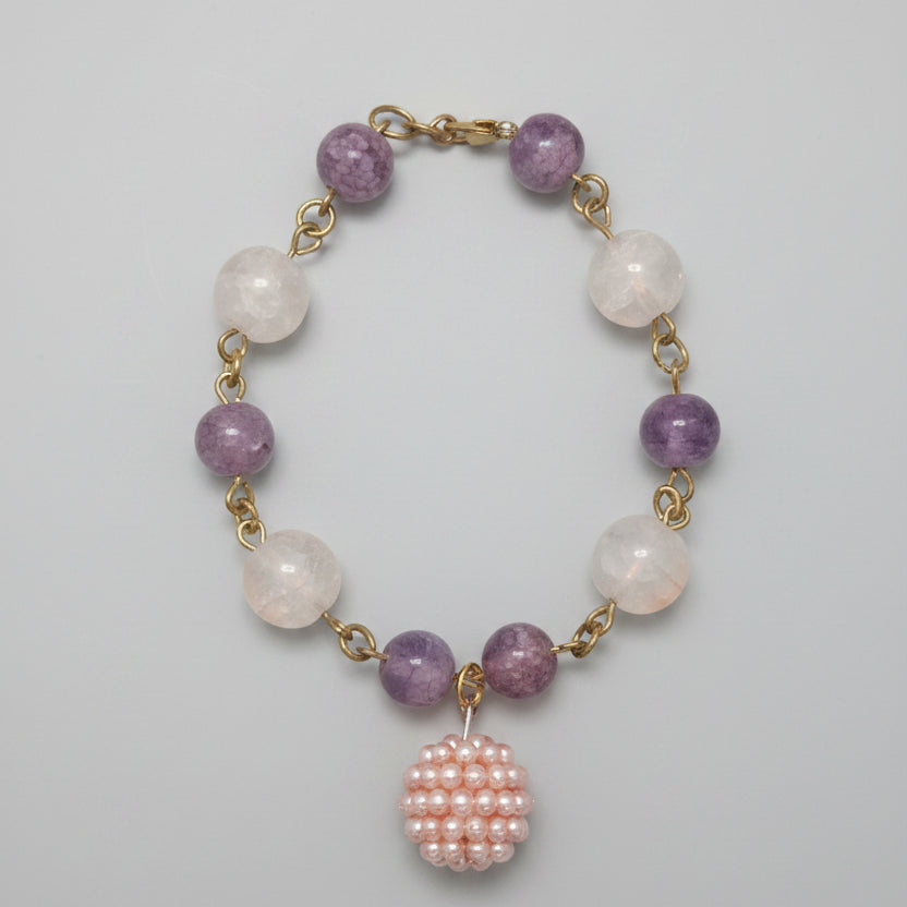 Necklace with pink and white beads on a gold chain displayed on a cardboard backing.