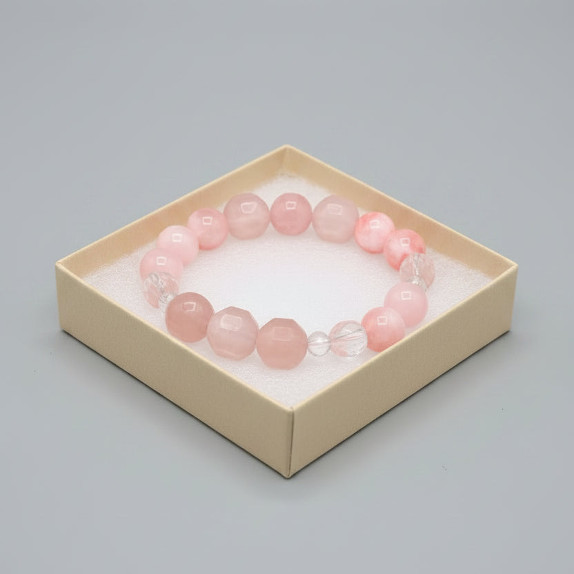 Pink beaded bracelet in a box with other bracelets on a dark surface