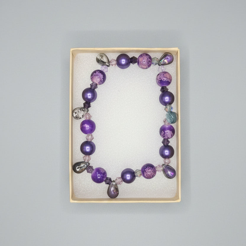 Purple beaded bracelet in a display box on a dark surface