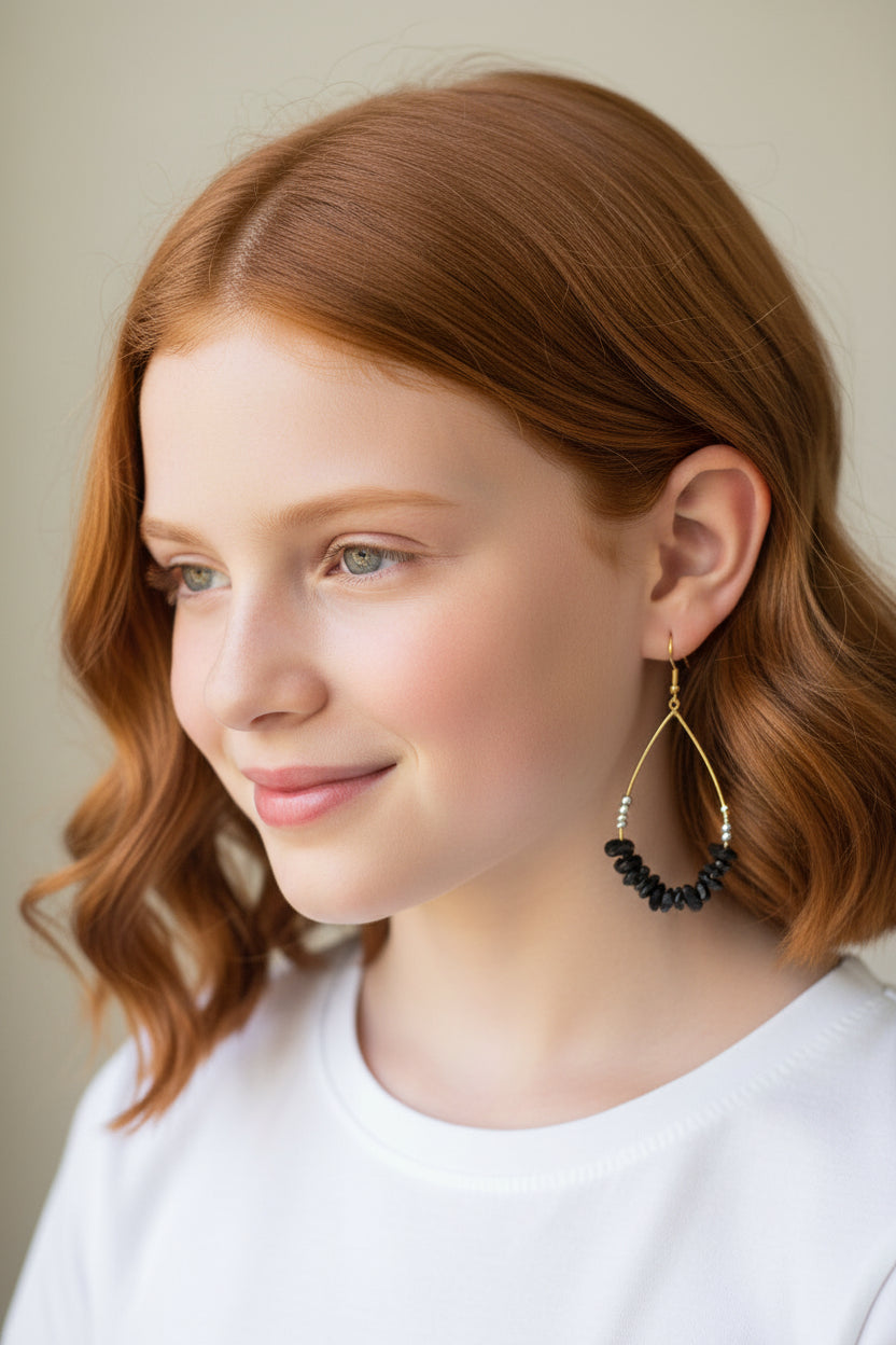 Woman wearing a black and silver earring with a neutral background