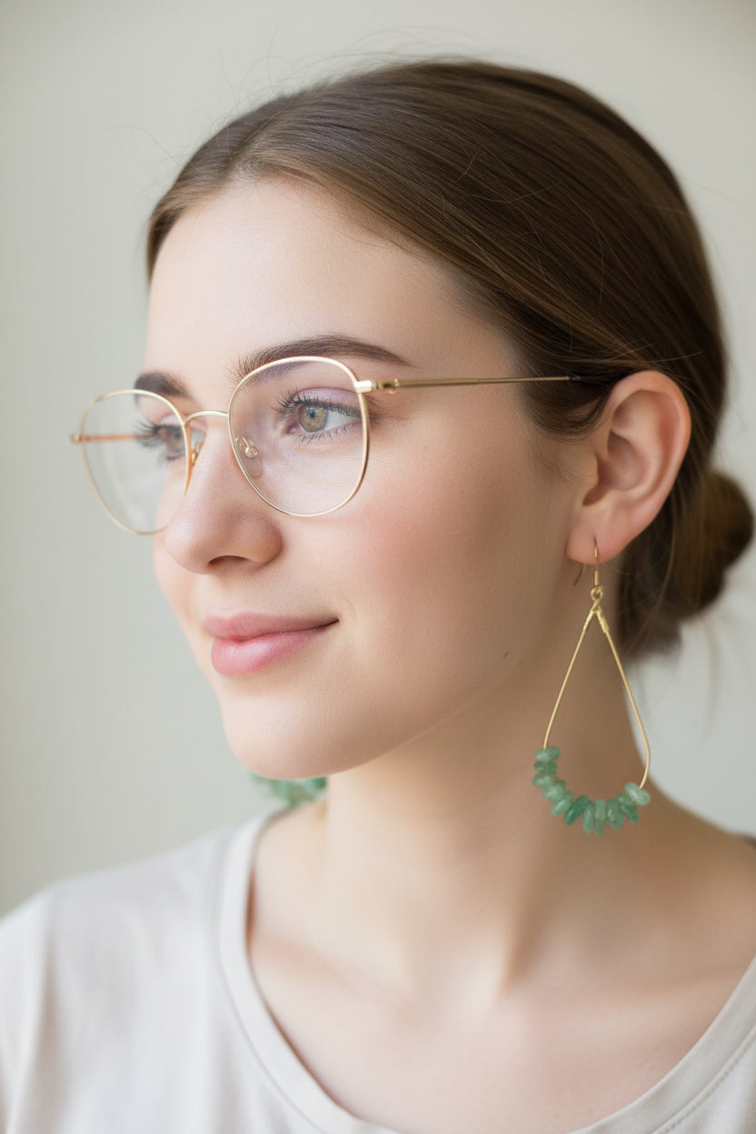 Gold earrings with green beads on a cardboard backing