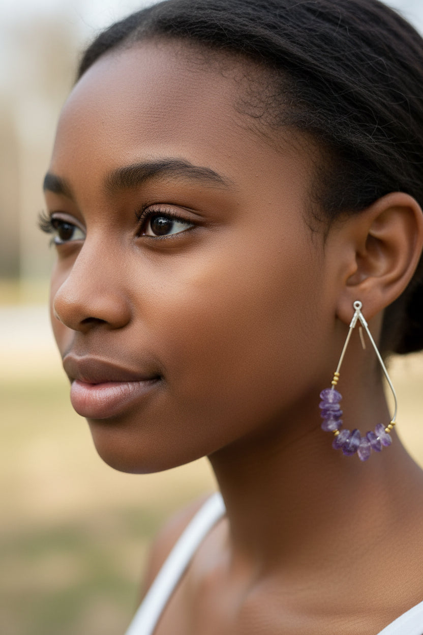 Purple beaded earrings on a clear card with a brown envelope background