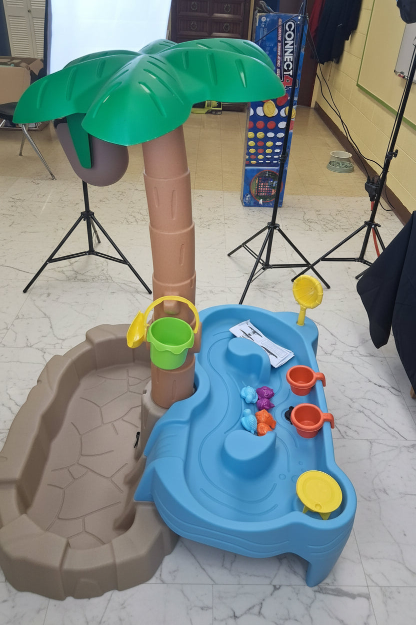 Children's play area with a palm tree and water table in an indoor setting.