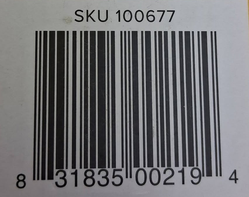 A close-up of a yellow surface with a white barcode label printed with the text 'SKU 100677' and a black barcode.